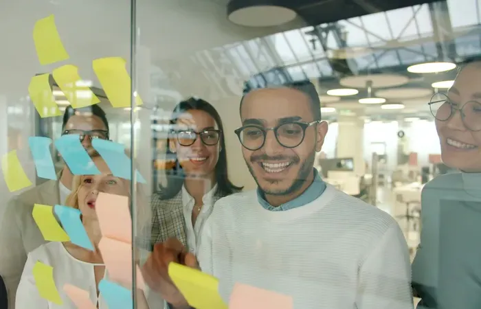 Group of diverse professionals smiling and collaborating during brainstorming session with sticky notes